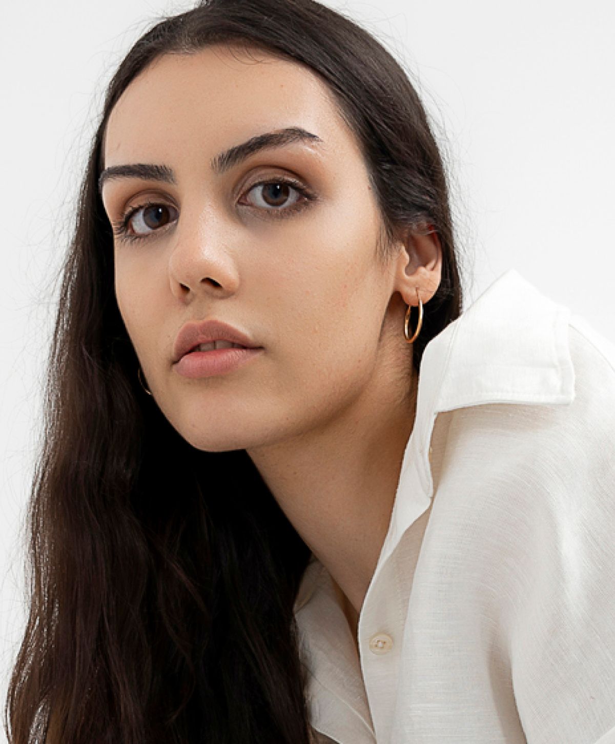 Young woman wearing a white shirt, serious expression.