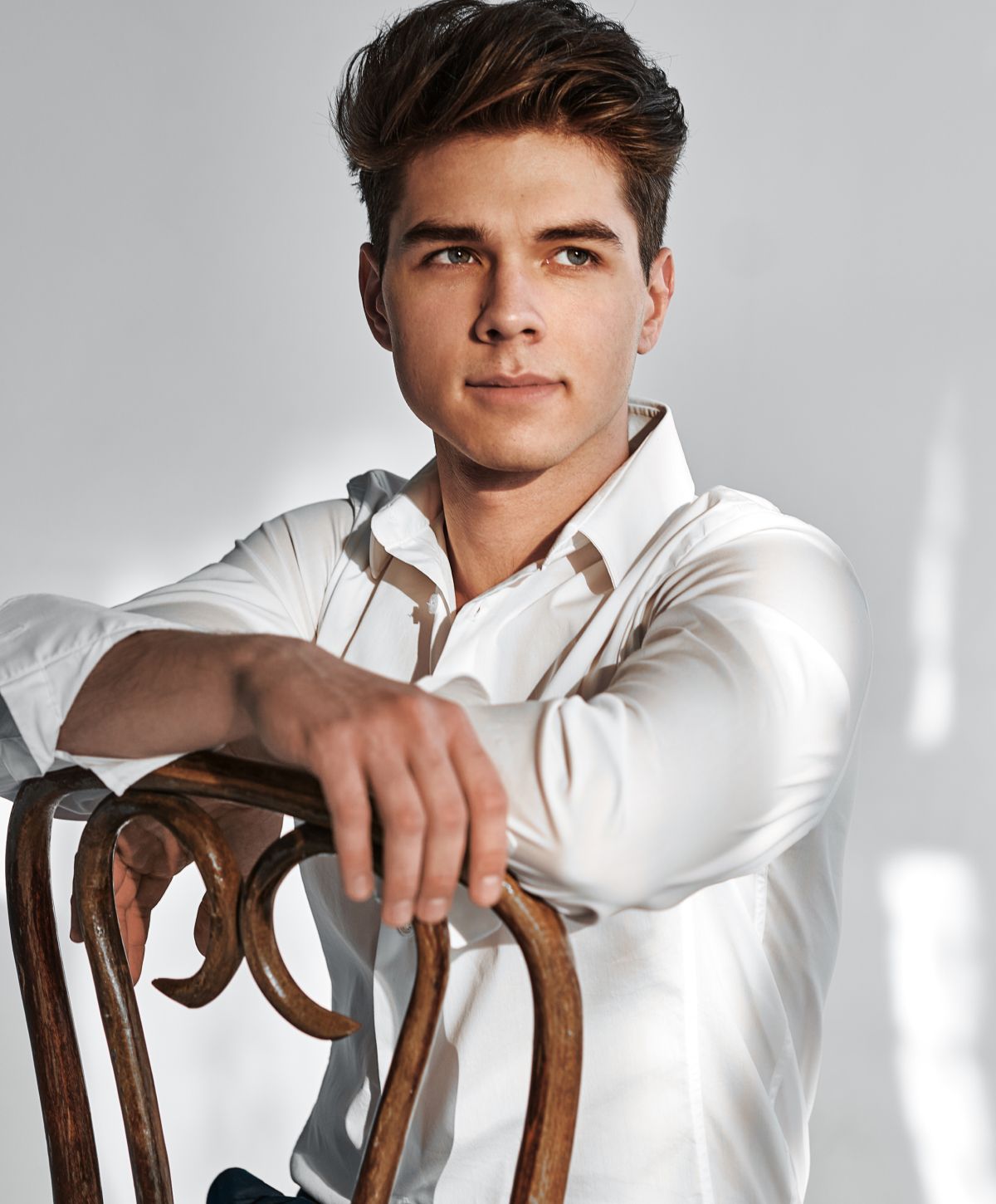 Young man in white shirt sitting on chair.