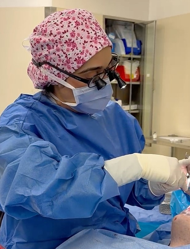 Surgeon performing a procedure in surgical attire.