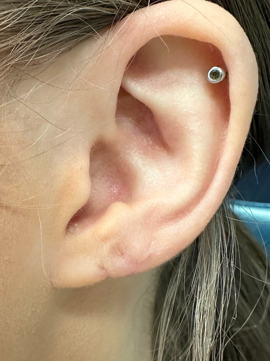 Close-up of ear with minimalist earring.