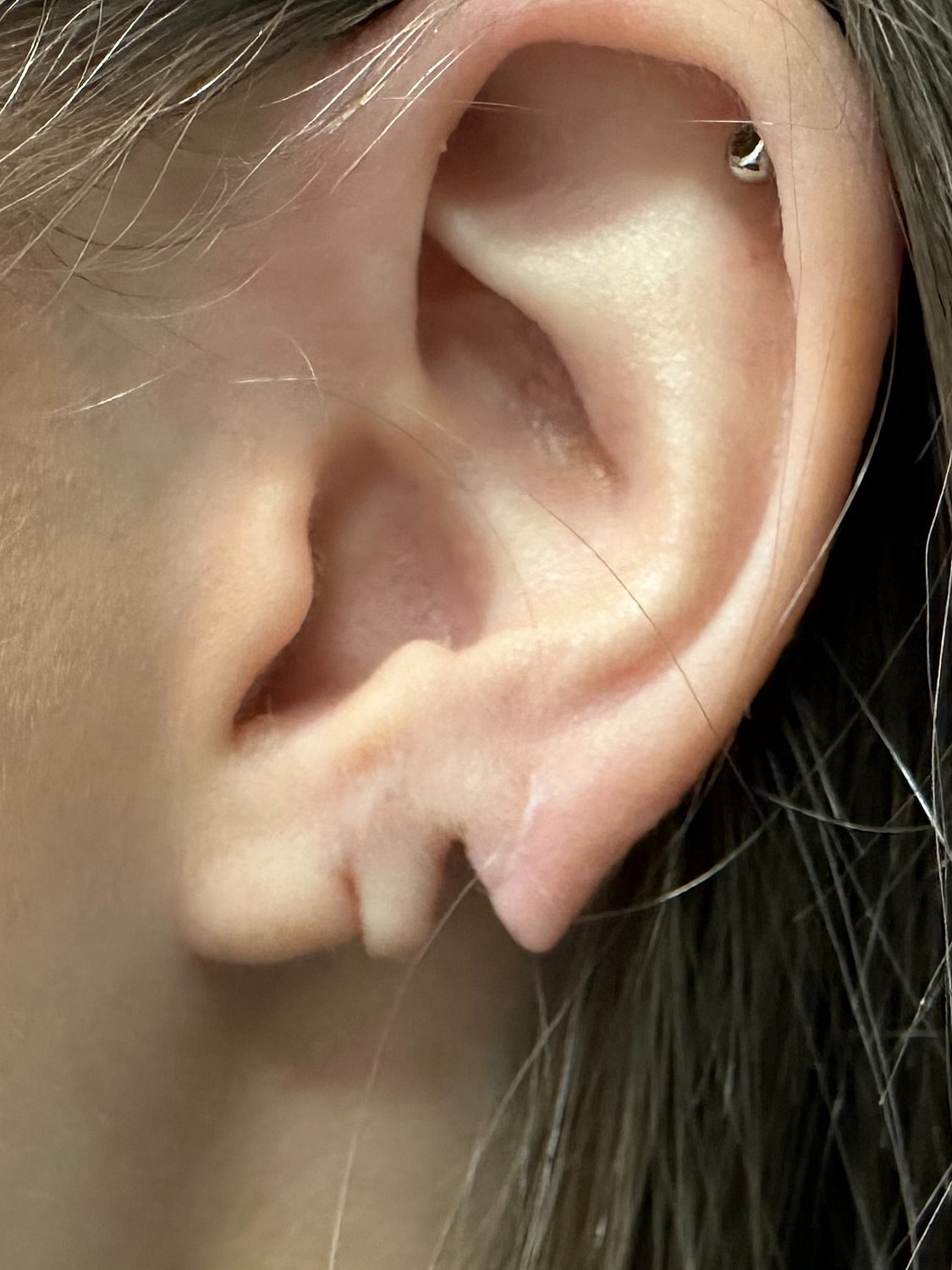 Close-up of human ear with earring.