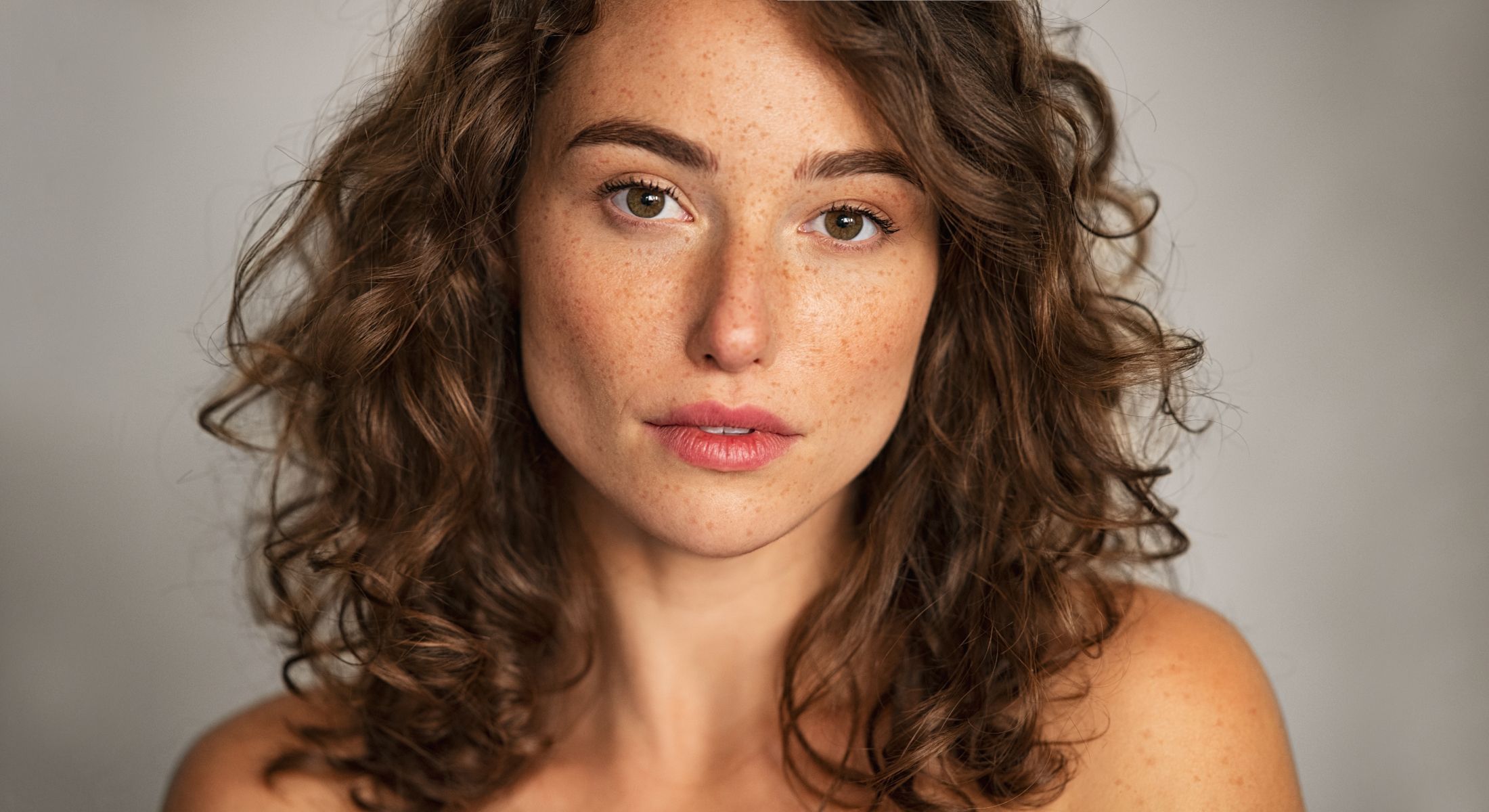 Woman with curly hair and freckles, close-up portrait.