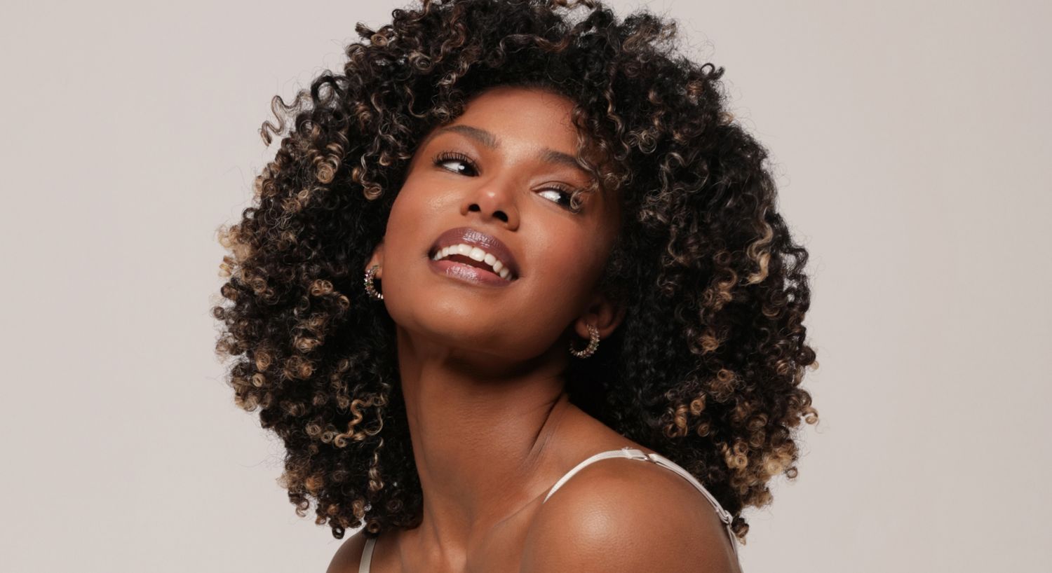 Smiling woman with curly hair on neutral background