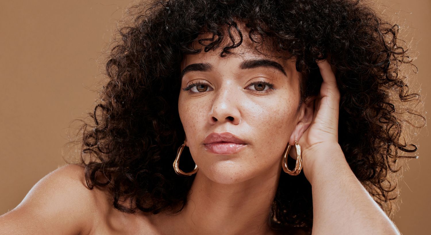 Woman with curly hair and hoop earrings.