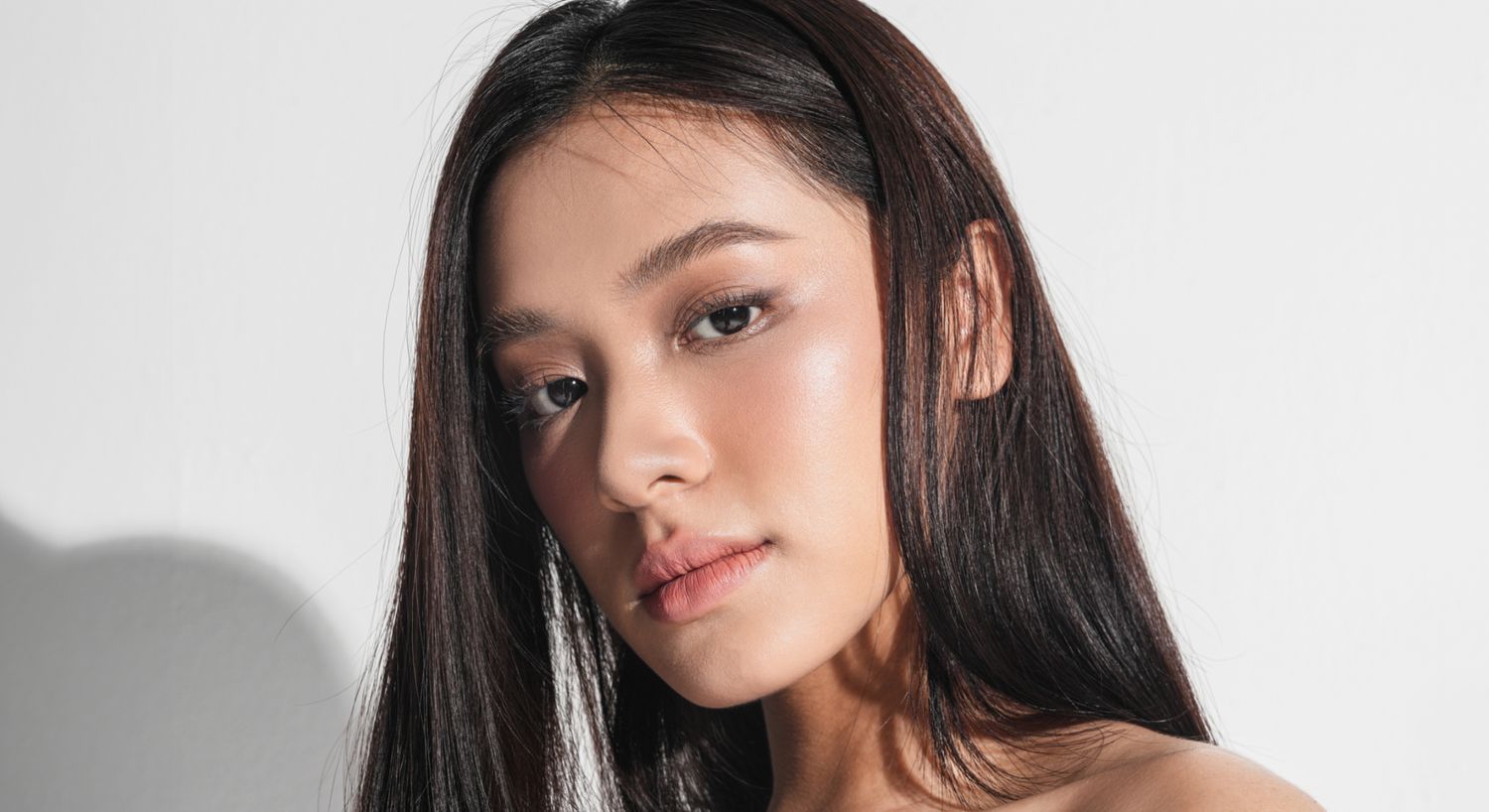 Young woman with long hair against white background.